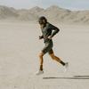Image of a bearded man with hat running in desert