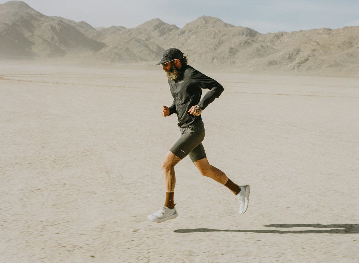 Image of a bearded man with hat running in desert